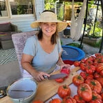 Woman sitting at a table with tomatoes and a hat on a patio