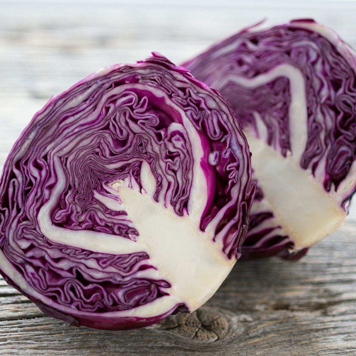 Two halves of a purple cabbage on a wooden surface