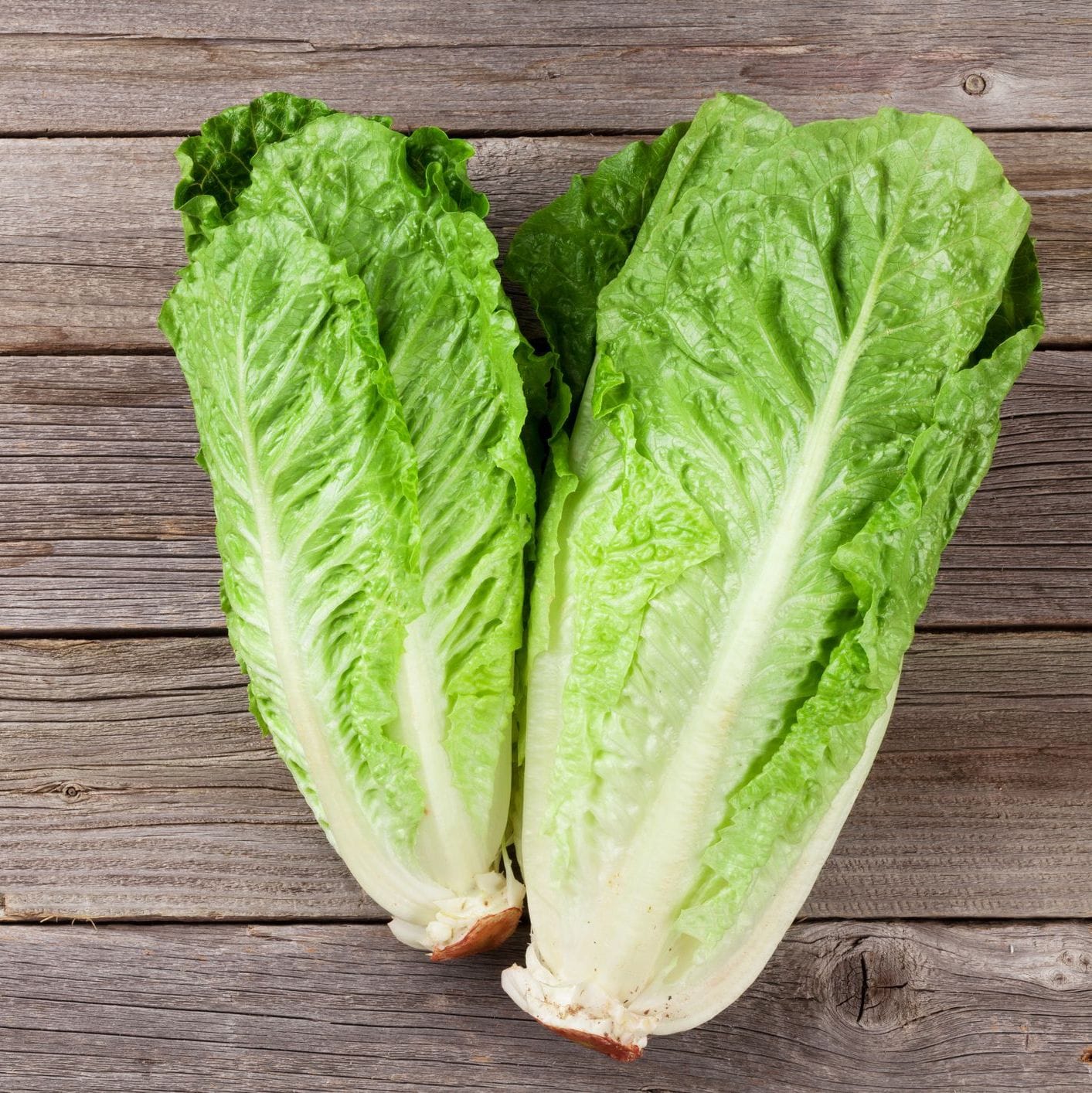 Two pieces of green lettuce on a wooden surface