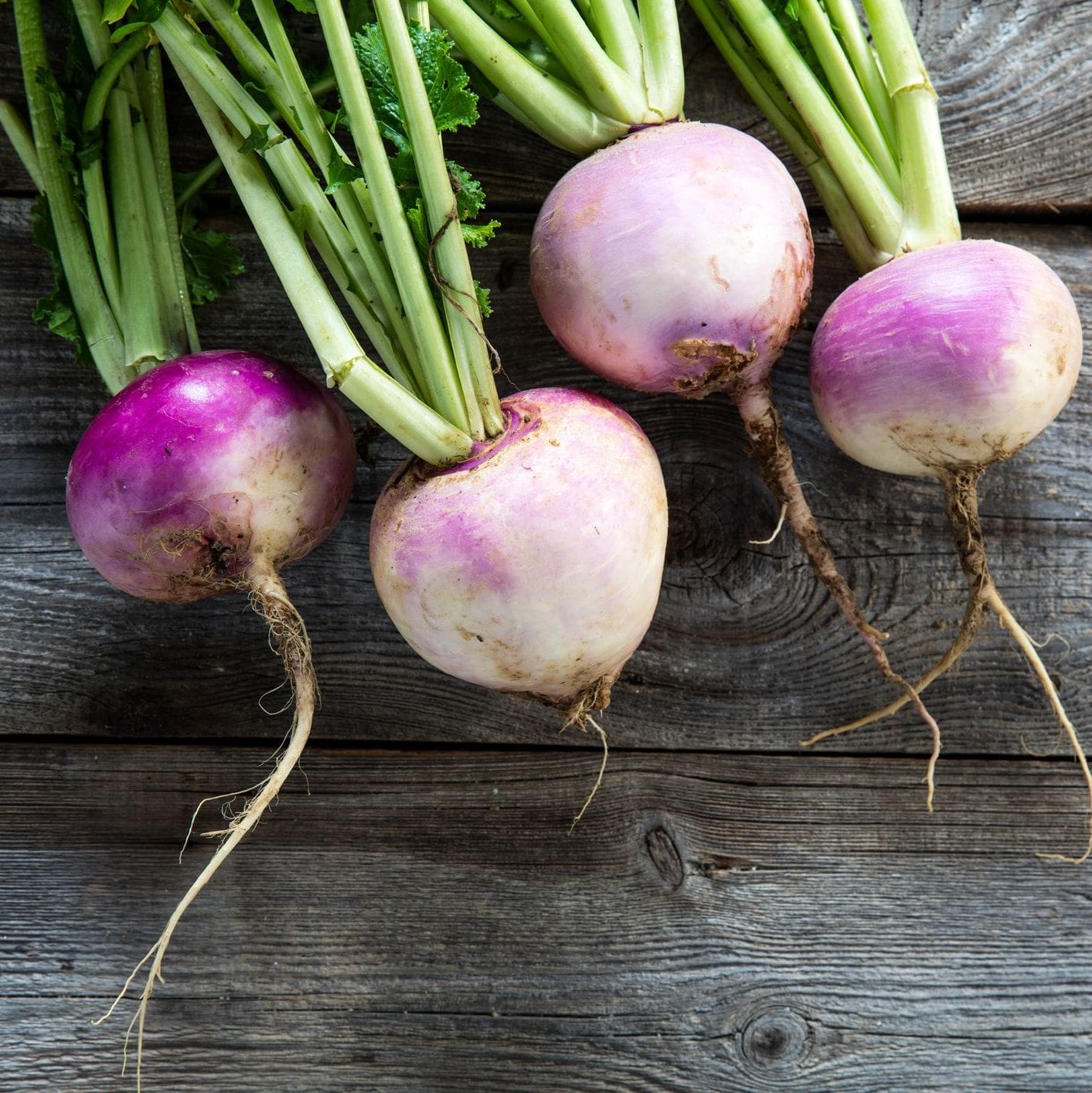 Turnips with green tops on a wooden surface